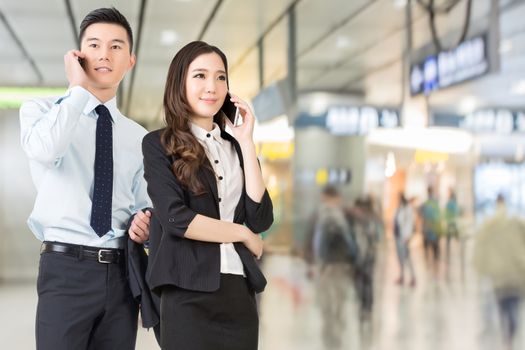 Asian business man and woman talking on cellphone in the station of Hong Kong, Asia.