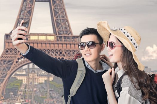 Asian couple travel and take a selfie at Eiffel Tower, Paris, France.