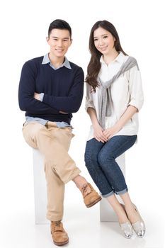 Attractive young Asian couple sit on boxes, full length portrait isolated on white background.