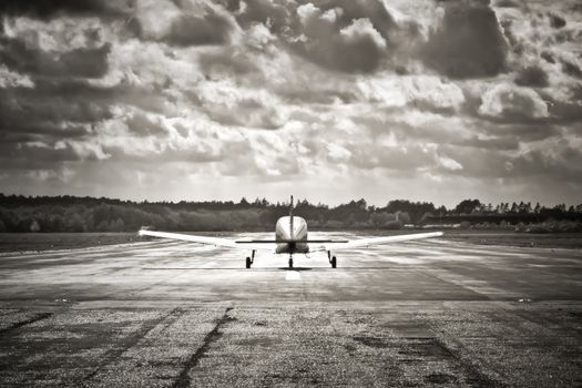 sepia toned propeller aircraft taking off into turbulant looking clouds