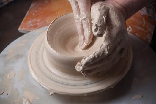 Hands of a potter, creating an earthen jar on the circle