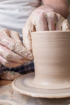 Hands of a potter, creating an earthen jar on the circle