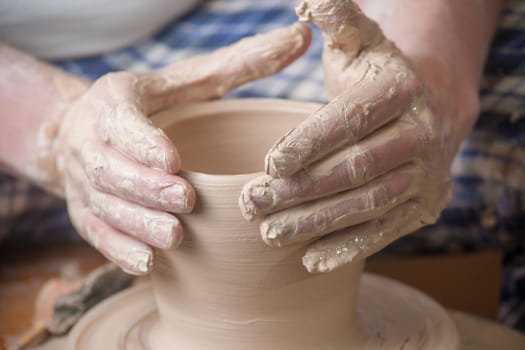 Hands of a potter, creating an earthen jar on the circle