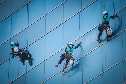 group of workers cleaning windows service on high rise building