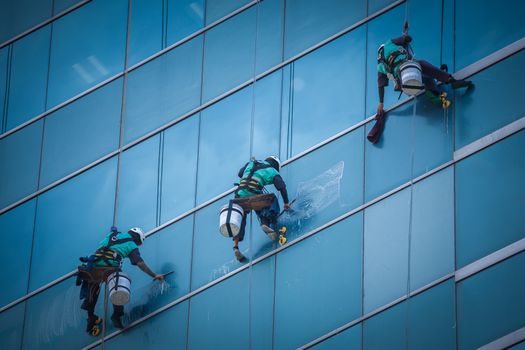 group of workers cleaning windows service on high rise building