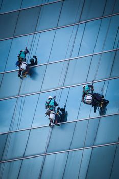 group of workers cleaning windows service on high rise building