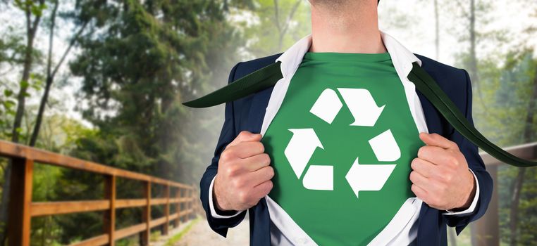 Businessman opening shirt in superhero style against bridge leading to forest