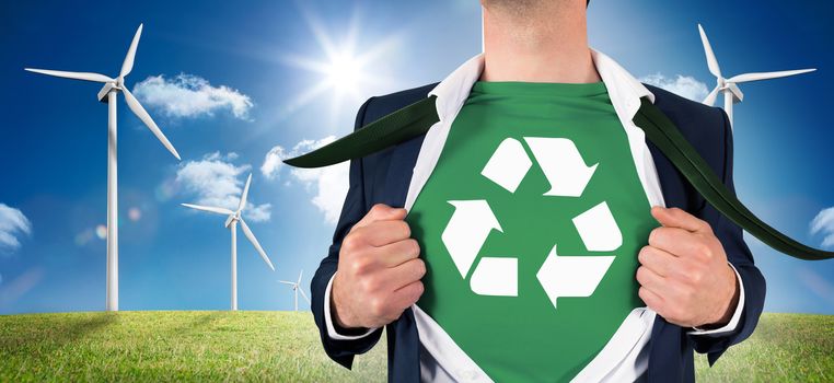 Businessman opening shirt in superhero style against digital landscape with three wind turbines