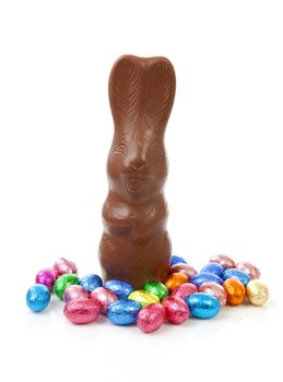 Milk chocolate easter bunny and colorful eggs over white background