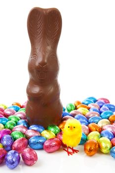 Milk chocolate easter bunny and colorful eggs over white background