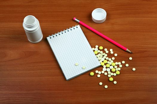 Writing Pad and the Pills on the Wooden Table closeup