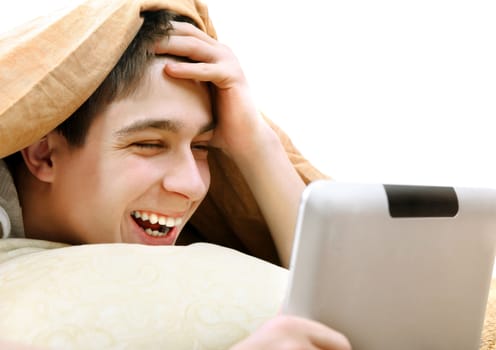 Cheerful Teenager with Tablet Computer under Blanket at the Home