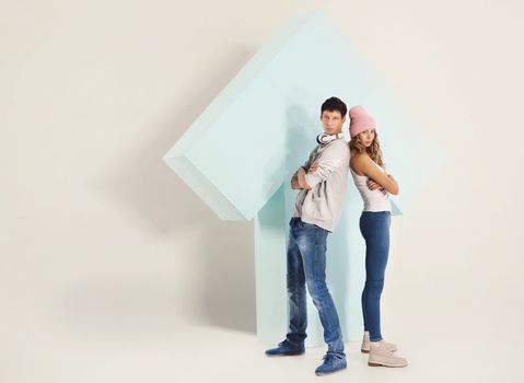 Girl and boy are standing under a big arrow back to back