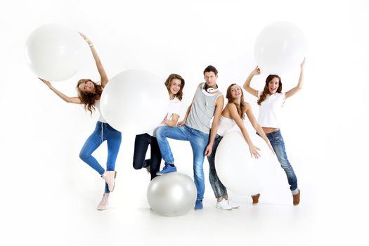 The team of five young people dressed in white shirt and jeans posing with giant balloons