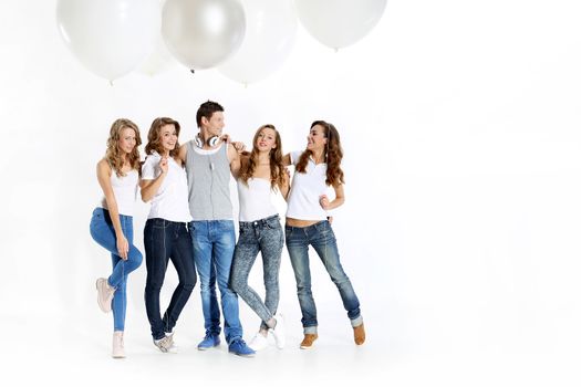 The team of five young people dressed in white shirt and jeans posing with giant balloons