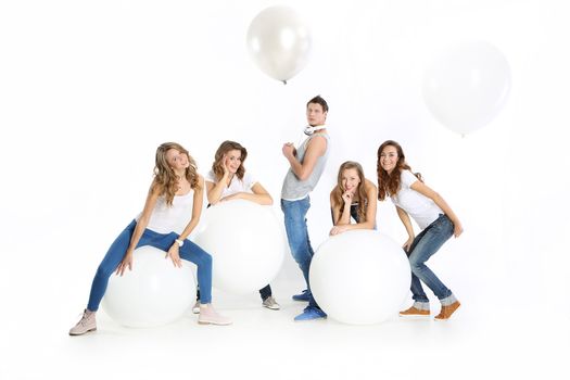 The team of five young people dressed in white shirt and jeans posing with giant balloons