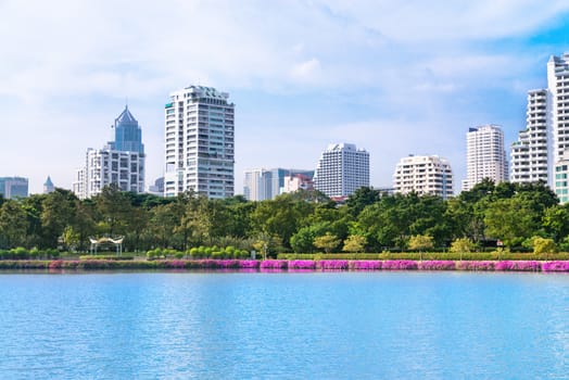 Modern city skyline of living district with park and lake in front  in day under blue sky
