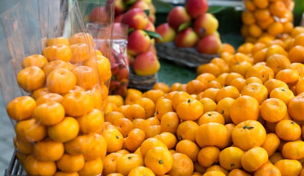 Small open street counter with fresh mandarin fruits partly packed in bags and apples on background