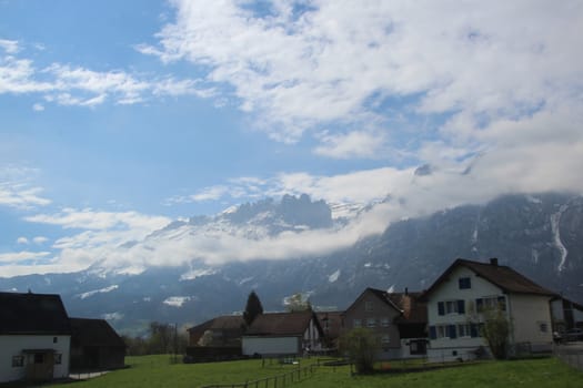 Typical swiss country side view of village homes with large Mountain backdrop.