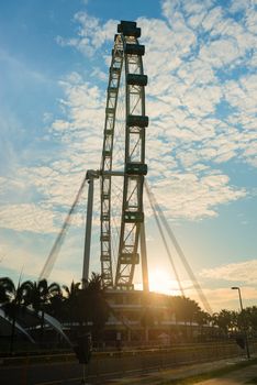 Silhouette of big ferris wheel with cabin with the morning sun on background