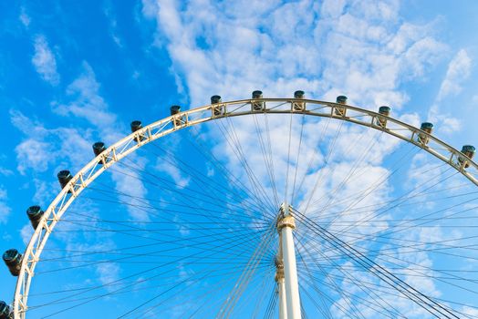 Big ferris wheel with cabin on blue sky with white clouds