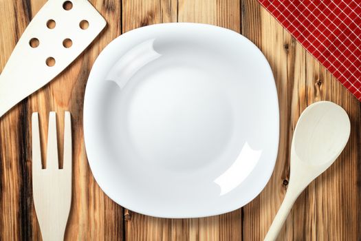 Empty plate on table background. Wooden cutlery and napkin. Top view