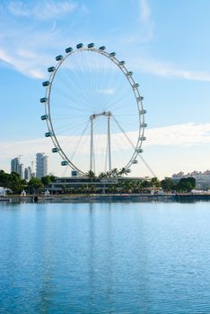 Big ferris wheel in the modern city skyline and bay water on front, Singapore. 