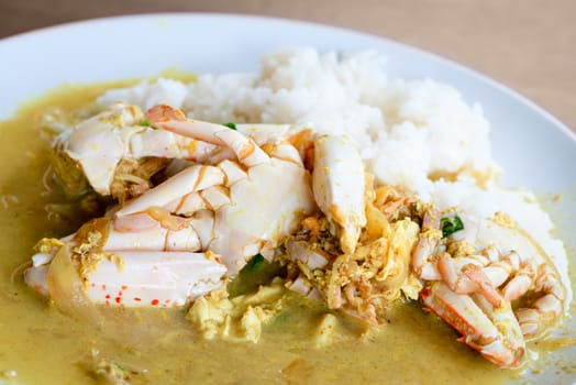 Cooked crabs with rice in yellow curry sauce with vegetables in white plate, thai food