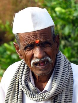 A poor old man from an Indian village with a wrinkled face aged with wisdom                               