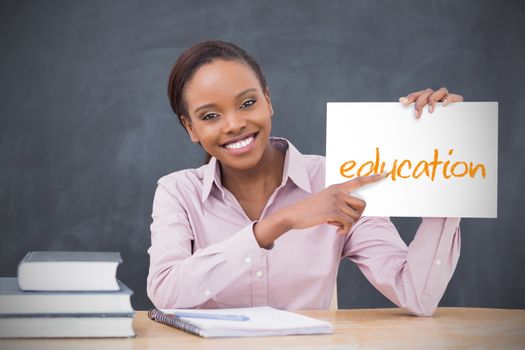 Happy teacher holding page showing education in her classroom at school