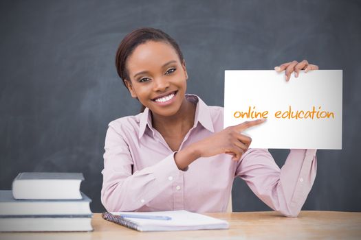 Happy teacher holding page showing online education in her classroom at school