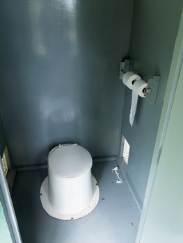 Campground pit toilet outhouse inside white plastic toilet and dirty interior to the toilet bowl