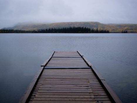 Twin Lakes, Yukon Territory, Canada, wooden floating boat dock on gray rainy day in autumn fall