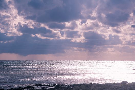 Shiny sea water, stormy clouds and rain away. Seascape.