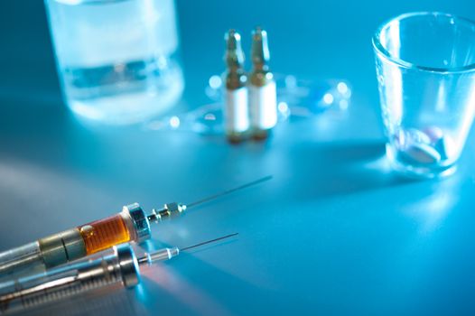 syringe with dose. medication vials, pills closeup, selective focus.