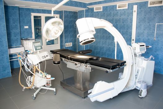 operating room with X-ray medical scan and equipment for artificial lung ventilation of patient.