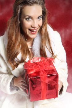 Beautiful happy woman with red gift,dressed in white fur