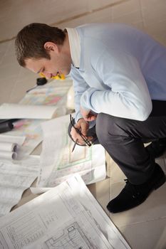 Architect looking drawings on the floor of the construction site.