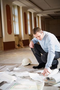 Architect looking blueprint on the floor of the reconstruction interior.