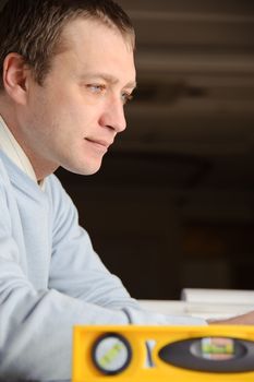 Portrait of engineer or architect in blue pullover is working on construction plans.