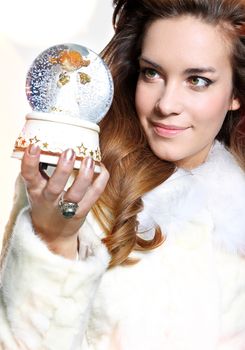 Happy Christmas woman in a white fur coat with glass music box