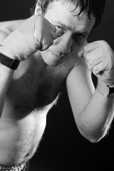 Boxer with a bruise in a battle position. Clenched fists. Dark background.