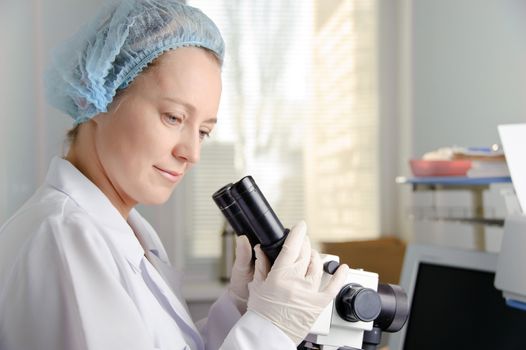 Female scientist working at the laboratory. White uniform and gloves.