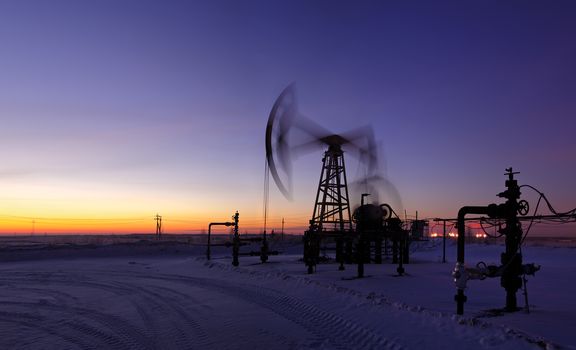 Pumpjack on the sunset sky background. Long exposure. Panorama.