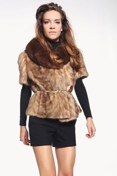 Beautiful fashion model posing in a fur vest and shorts