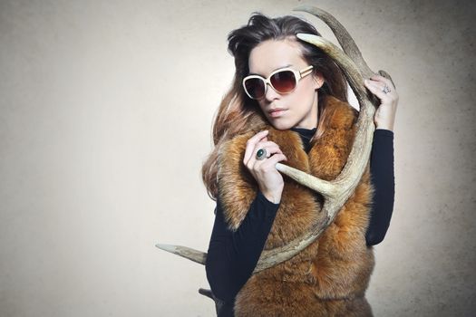 Beautiful fashionable woman in elegant fur coat with deer horn