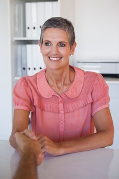 Casual business people shaking hands at desk in her office