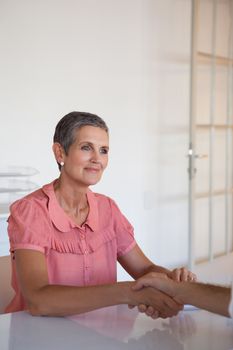 Casual business people shaking hands at desk in her office