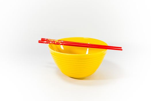 yellow ceramic bowl and red chopsticks on white scene,shallow focus