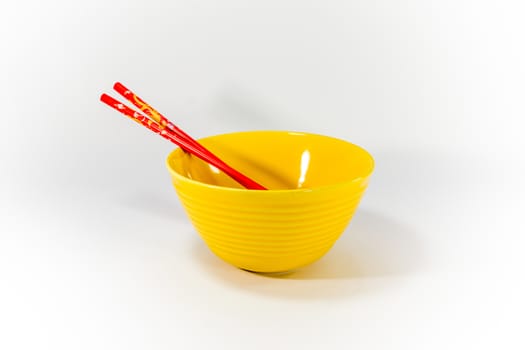 yellow ceramic bowl and red chopsticks on white scene,shallow focus